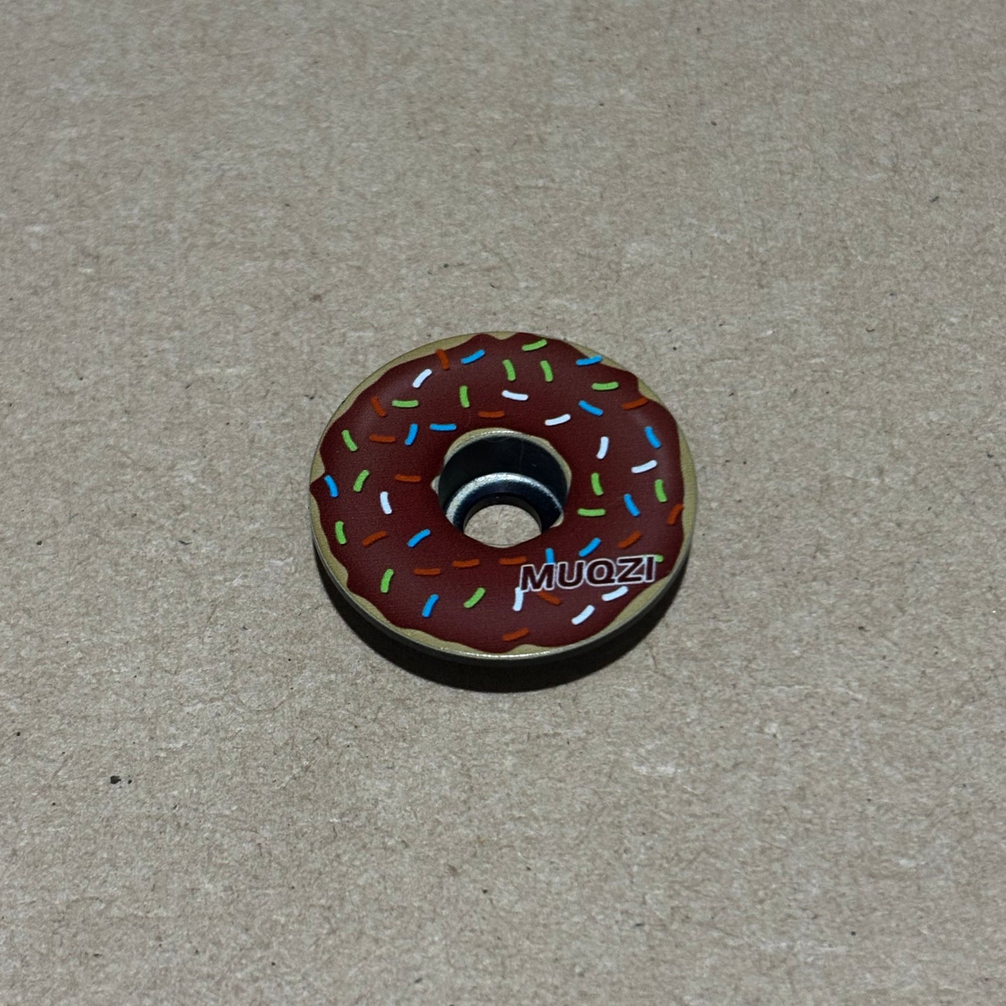 Donut-shaped object with sprinkles on a gray background